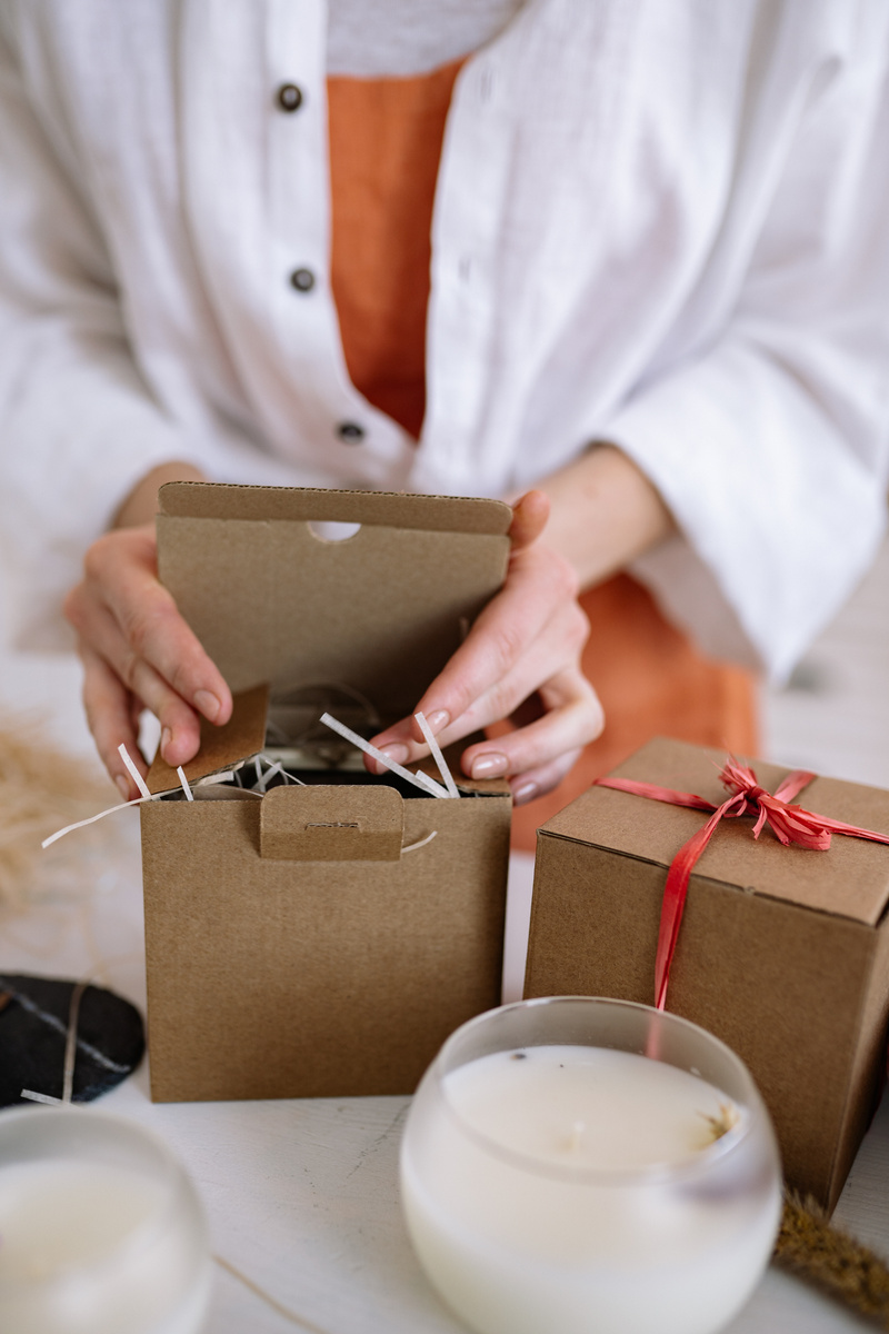A Person in White Button Up Shirt Closing the Lid of a Cardboard Box